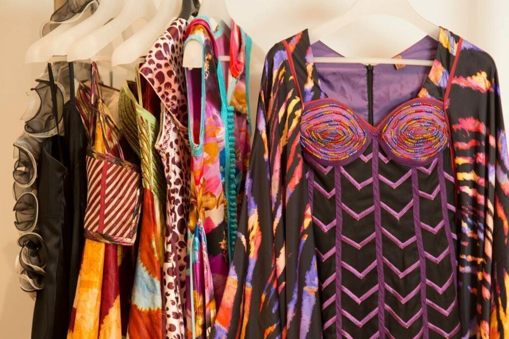 Des habits de la collection Alphadi sur cintres.